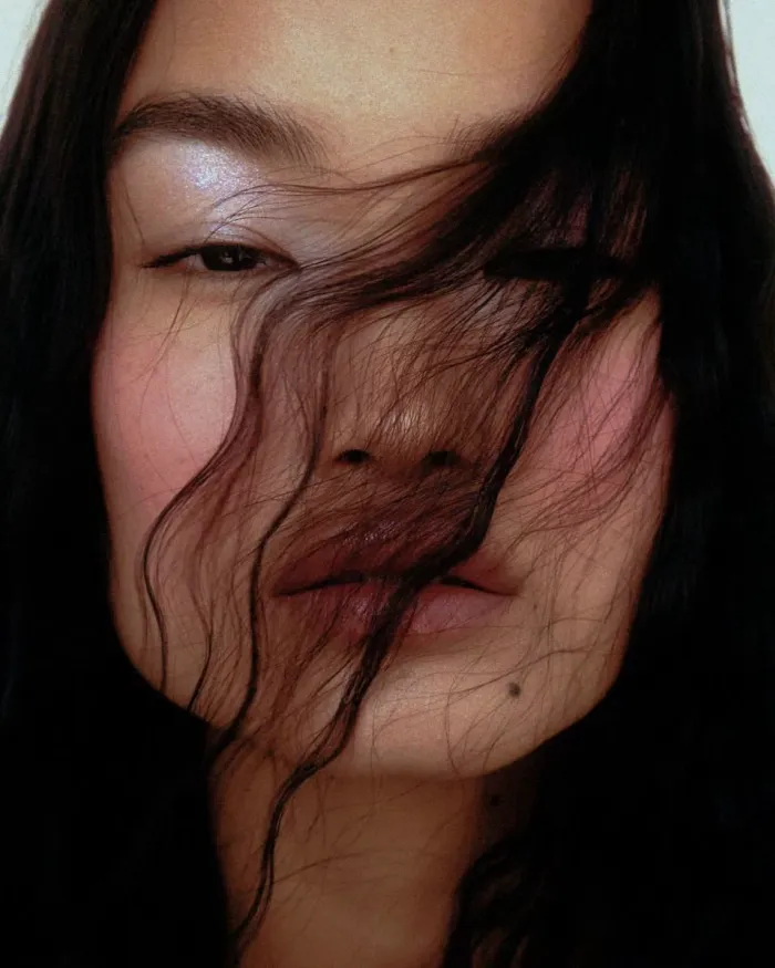 Close-up of a woman with dark hair falling across her face